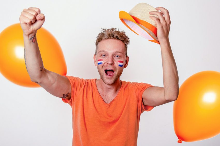 a man is holding balloons and a hat